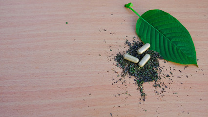 capsule of kratom leaf (Mitragyna speciosa) Mitragynine on wooden table ,Drugs and Narcotics,Thai herbal which encourage health