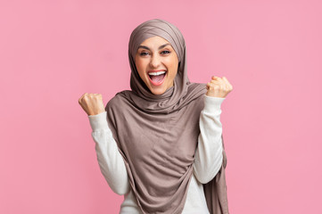 Overjoyed Arabic Girl In Headscarf Celebrating Success Over Pink Background.