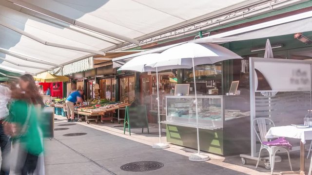 Famous Viennese Naschmarkt food market timelapse with customers stralling between the vegetable and fish stalls in Vienna, Austria. Chairs and umbrellas