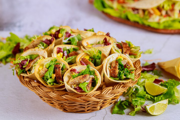 Tortillas cone stuffed with vegetable and meat on basket with green salad. Mexican cuisine.