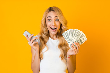 Money online. Excited woman holding smartphone and bunch of money