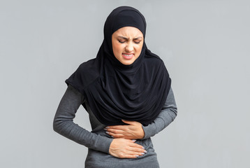 Arabic woman in hijab suffering from abdominal pain