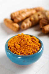 Food and drink, diet nutrition, health care concept. Raw organic orange turmeric root and powder, curcuma longa on a grunge cooking table. Indian oriental low cholesterol spices