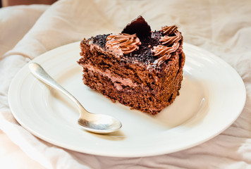 A slice of delicious chocolate cake on a white linen tablecloth. Close up. Sweet dessert. Winter Christmas New Year Holiday food concept