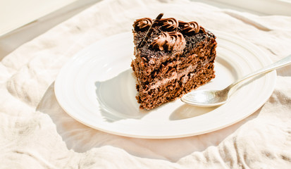 Freshly made delicious chocolate cake on a white linen tablecloth background. Kinfolk and sweet food atmosphere concept. Close up. Horizontal