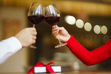 Couple clink glasses with red wine. Lovers give each other gifts.  Romance at restaurant for Valentine's Day concept. Relationship & Birthday concept.