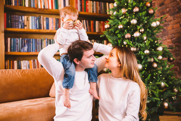 Family Christmas Concept. Lovely family sits near Christmas tree on winter evening. Happy family with son on floor near sofa At home. Family At Home At New Year Time. family enjoy new year holidays