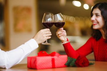 Couple clink glasses with red wine. Lovers give each other gifts. Lovely romantic dinner. Romance at restaurant for Valentine's Day concept. Relationship, surprise, Birthday concept.