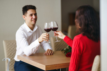 Couple clink glasses with red wine. Lovers give each other gifts. Lovely romantic dinner. Romance at restaurant for Valentine's Day concept. Relationship, surprise, Birthday concept.