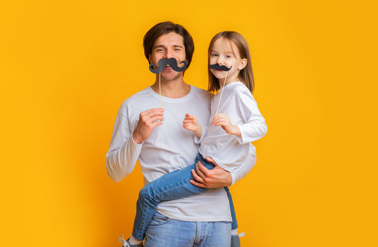 Funny girl and dad have mustaches on sticks