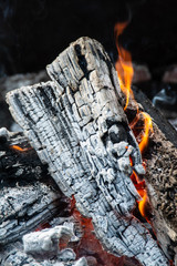 Warm and inviting close up of fire pit wood burning featuring flame and ash