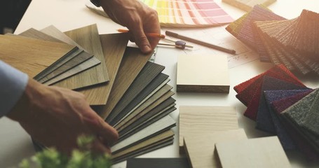 interior designer choosing flooring and furniture materials from samples for home interior design project in office