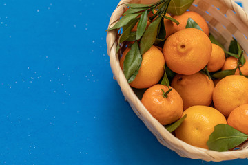 Tangerine with leaves is on a blue background. Natural Vitamin C. Fresh citrus fruit. Flat lay. Copy space.