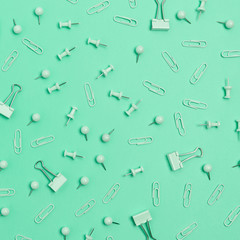 Pattern made of paper clips and push pins on mint background. Monochromatic concept.