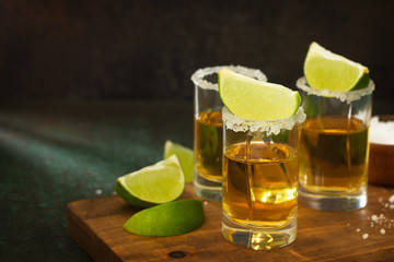 Mexican Gold Tequila shot with lime and salt on dark stone background. Copy space.