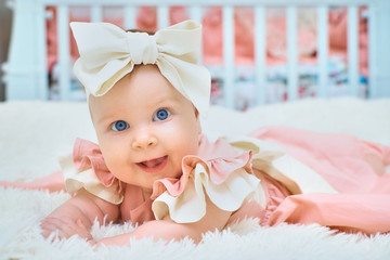 A little girl with a bow on her head is lying on the bed