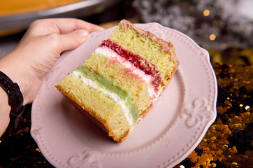 Golden brilliant tasty cake is cut into pieces. A slice of cake on a pink plate. Homemade baking for a children's party.