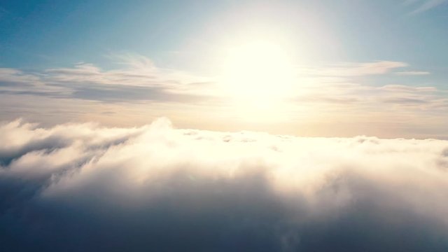 Aerial view up from the clouds to the sky in motion. Aerial view white clouds in blue sky during sunrise or sunset. Aerial top view cloudscape. Texture of clouds. Panoramic view. Clouds in motion