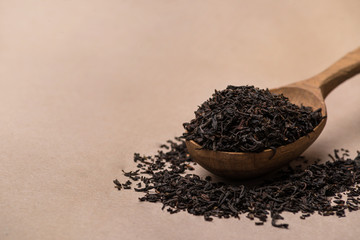 black tea in spoon close-up on paper background