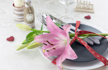 Serving, table decoration Valentine's Day. Table set, fork, knife, plates and lily.