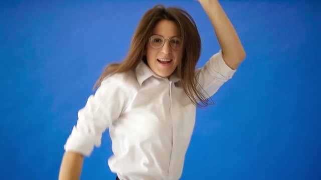 Funny business woman in a white shirt and glasses dancing on a blue phantom background