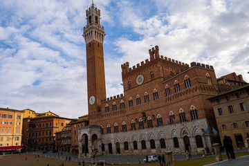 Fototapeta na wymiar La Torre del Mangia, ubicada en la Piazza del Campo, es la torre cívica del Palazzo Pubblico. Construida en siglo XIV y con una altura de 88 metros, es la tercera Torre Medieval más alta de Italia.