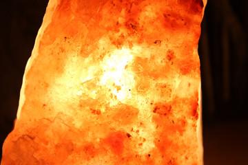 Himalayan salt lamp on wooden table illuminated in a darkend room