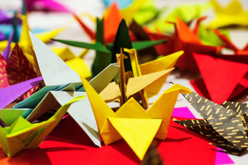 Color paper cranes of origami from paper.Multi-colored origami in the form of cranes on the table. Origami symbol.