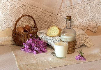 The basket with eggs and wild flowers, milk and bread on the table close-up
