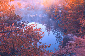 Early foggy morning. Sunrise over a lake with a rocky shore. Nature landscape in autumn