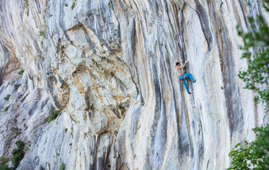 Caucasian young man climbing challenging route on cliff