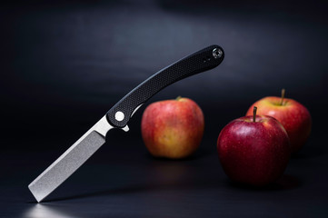 A knife and a lot of red apples. Apples on a black background.