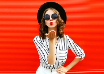 Portrait beautiful young woman blowing red lips sending sweet air kiss wearing white striped shirt,...