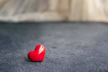 Red heart on dark textured table near window. Selective focus, copy space. Love, Romance, Valentine's Day concept. Greeting card.