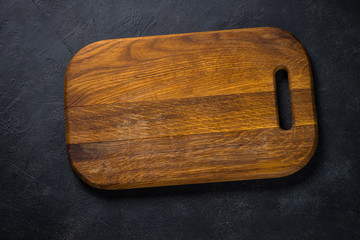 Black wooden cutting board on black table.