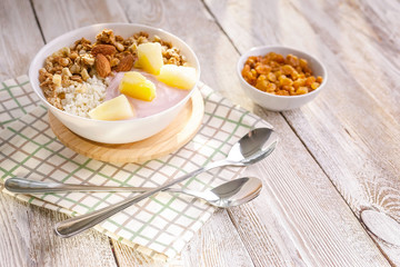Baked granola with nuts, cottage cheese, strawberry yogurt and pineapple slices in a plate on a checkered napkin. The light of the morning sun. Healthy breakfast