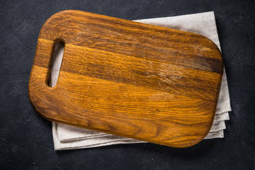 Black wooden cutting board on black table.