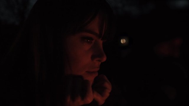 Woman Looking at Campfire in the Dark Outside
