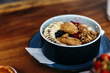 Healthy vegan breakfast with oatmeal bowl with banana, peanut butter, blackberries, raspberries, nuts, seeds and goji berries.