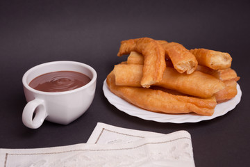 Churros caseros  en un plato con una taza de chocolate.