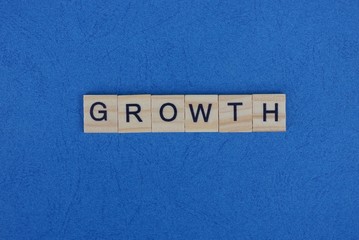 gray word growth from small wooden letters on a blue table