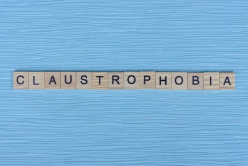  gray word claustrophobia from small wooden letters on a blue table