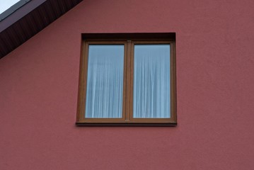 one brown large window on the plastered red wall of a private house on the street