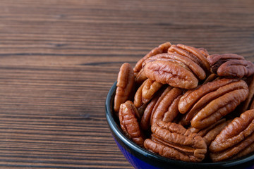 Pecan nuts in a blue bowl on a brown wooden table