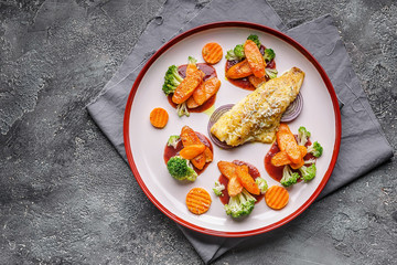 Top view fillet of sea bass with vegetables. Baked fish, cauliflower and carrots on a big plate. Copy space