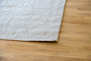 Close up of crumpled carpet laying on parquet wooden floor.