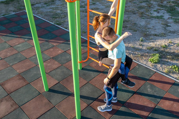 Young fit athlete working out at outdoor gym making dipping pull ups exercise using dip rings with...