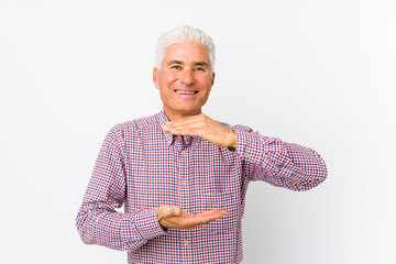 Senior caucasian man isolated holding something with both hands, product presentation.