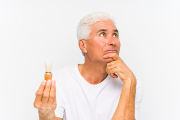 Senior caucasian man recently shaved looking sideways with doubtful and skeptical expression.