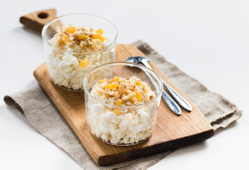 Crumbly cottage cheese with honey, banana, golden raisins and nuts on a light background
